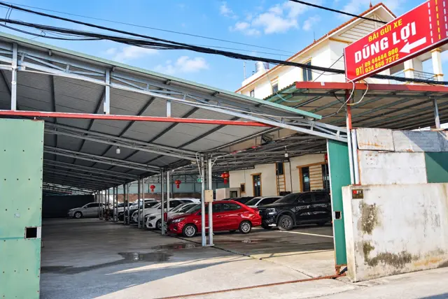 Cổng vào bãi gửi xe ô tô Dũng Lợi với biển hiệu đỏ và số điện thoại, gần sân bay Nội Bài